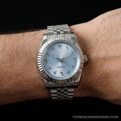 Reloj automático plateado con esfera azul en la muñeca