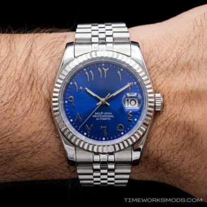 Reloj automático azul con números árabes en la muñeca