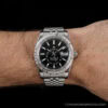 Silver wristwatch with a black dial on the wrist