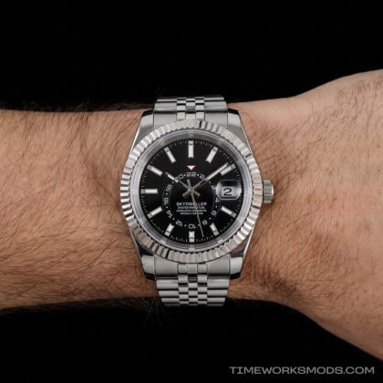 Reloj de pulsera plateado con esfera negra en muñeca
