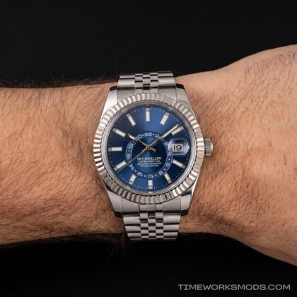 Reloj de lujo azul con brazalete metálico en la muñeca