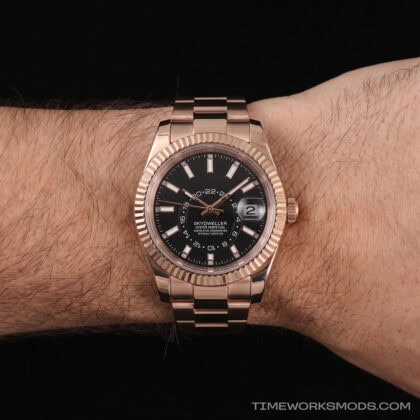 Reloj de pulsera dorado con esfera negra en muñeca