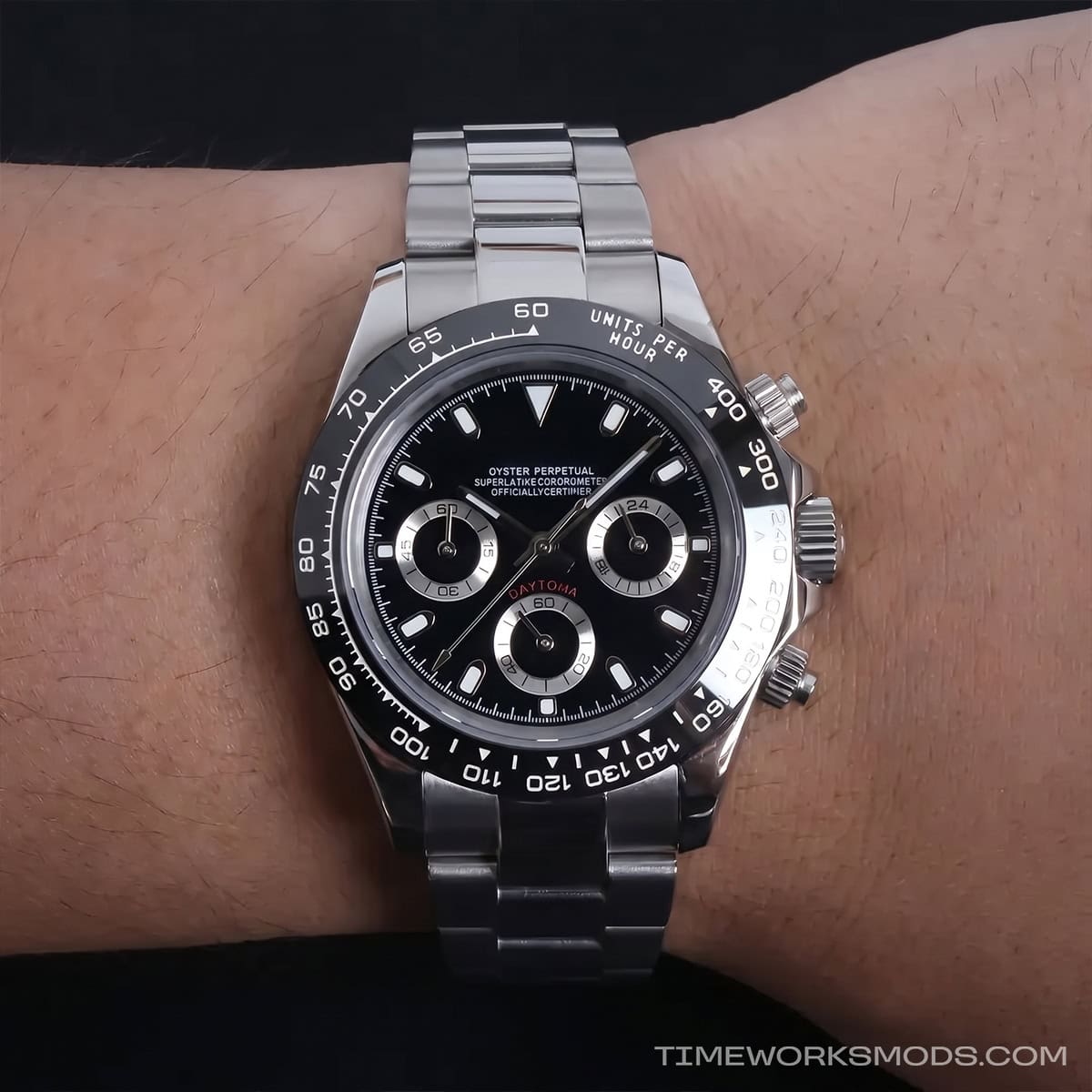 Reloj cronógrafo de acero con esfera negra en muñeca